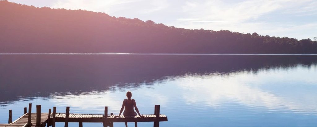 person sitting on a dock looking at a lake
